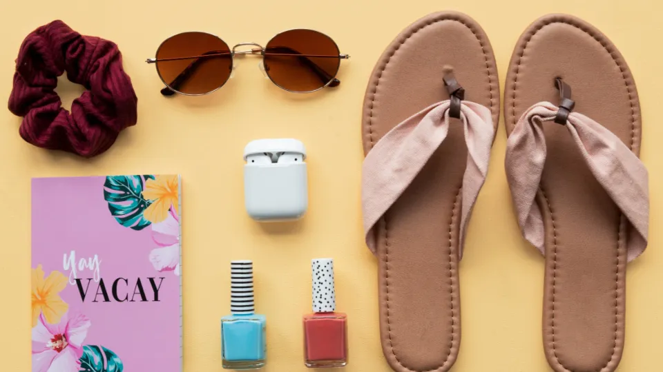 Flatlay med nagellack, hårsnodd och anteckningsbok på gul botten